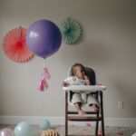 girl in white shirt lying on white and pink high chair