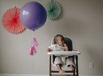 girl in white shirt lying on white and pink high chair