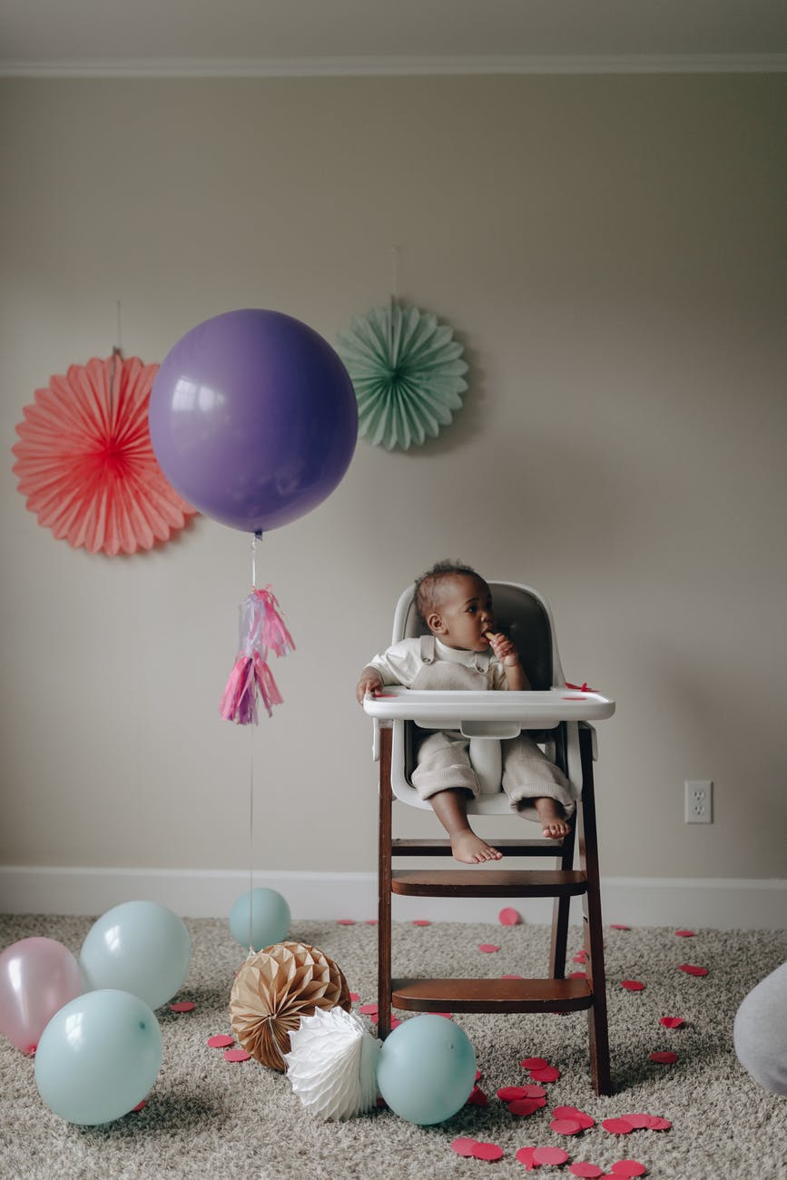 girl in white shirt lying on white and pink high chair